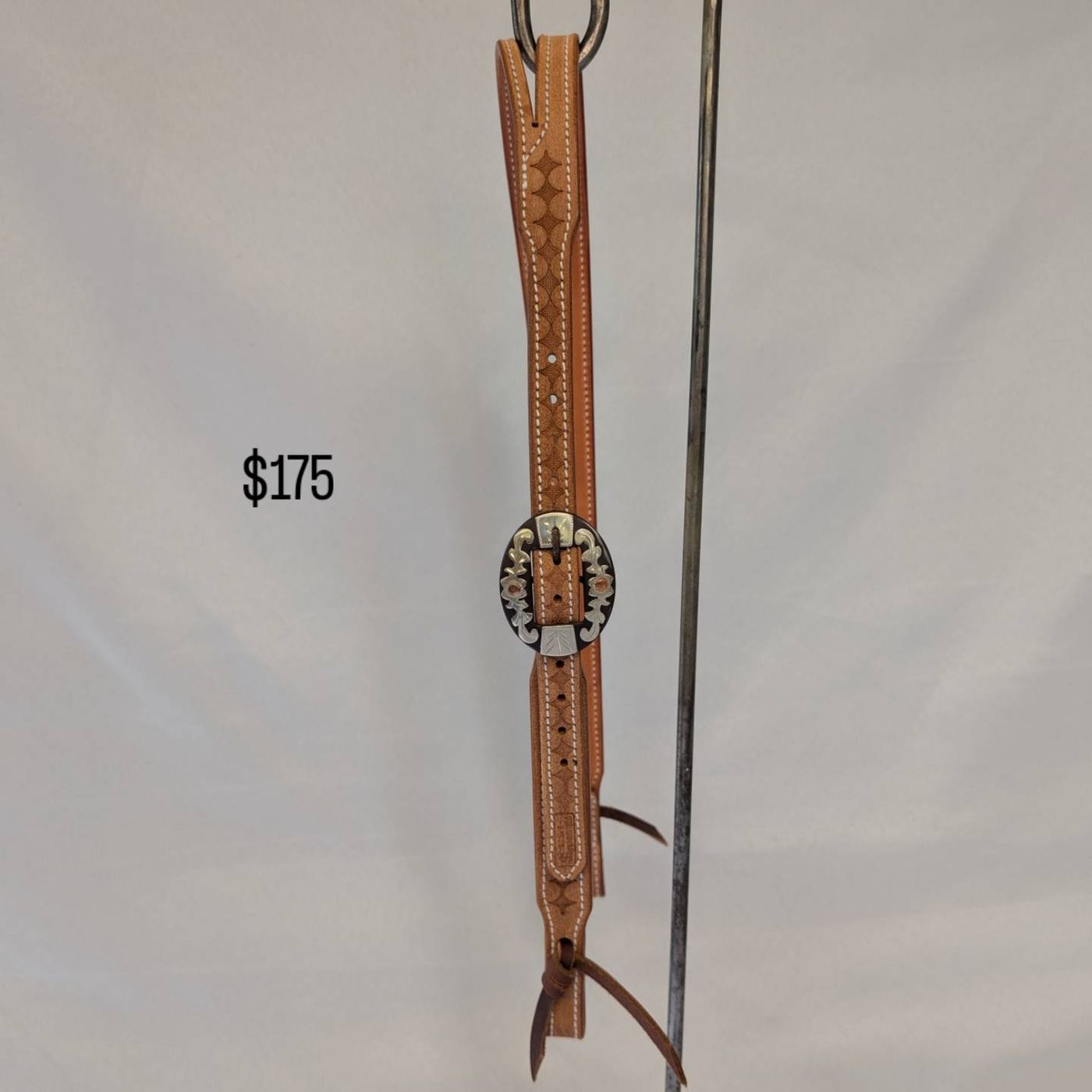 Tan floral-stamped headstall with engraved silver buckle, number 1