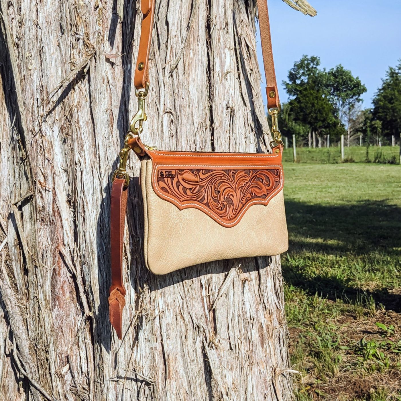 Tooled leather crossbody purse hanging on a tree
